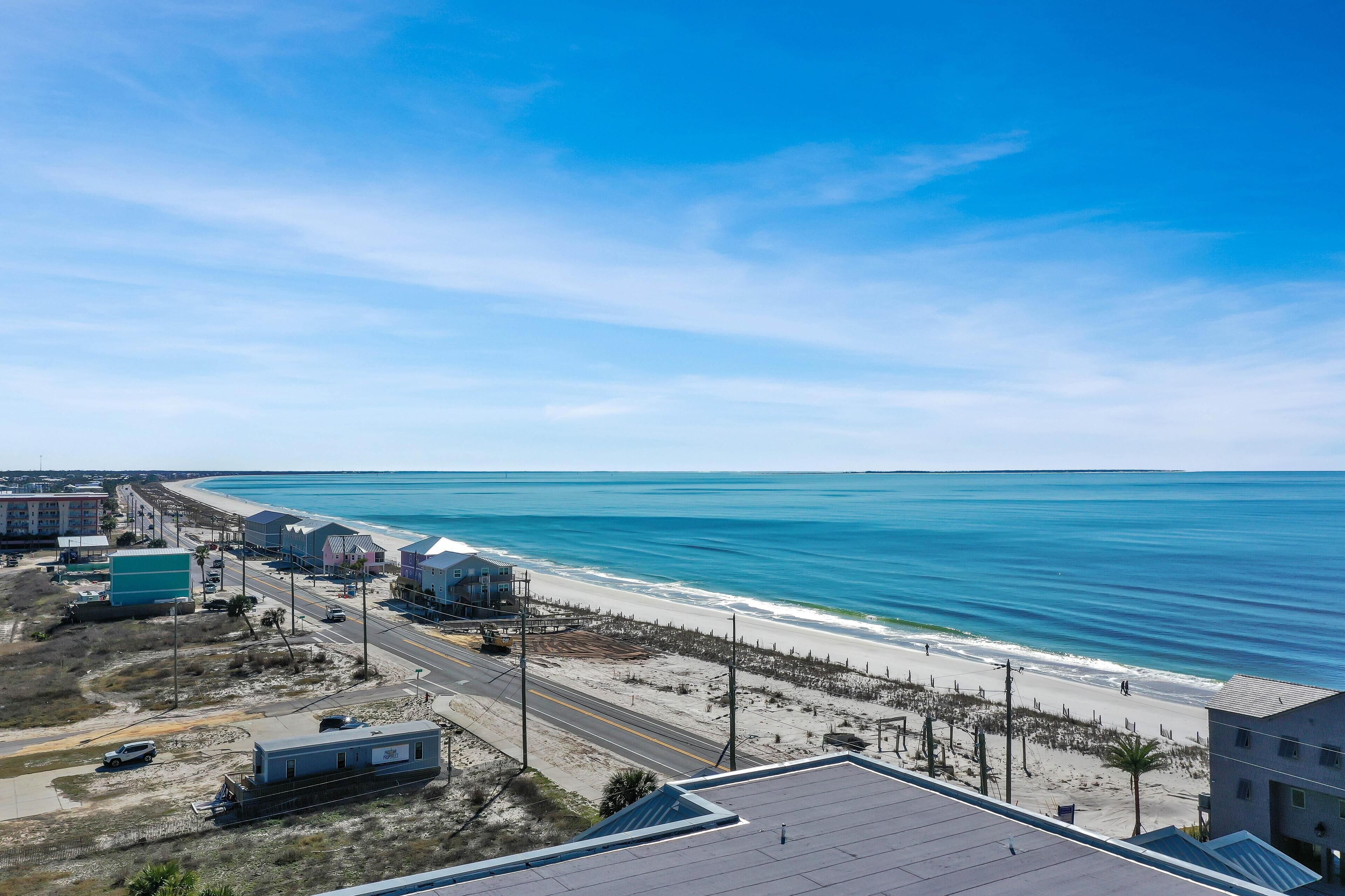 A coastal view with a beach, buildings, and a road.