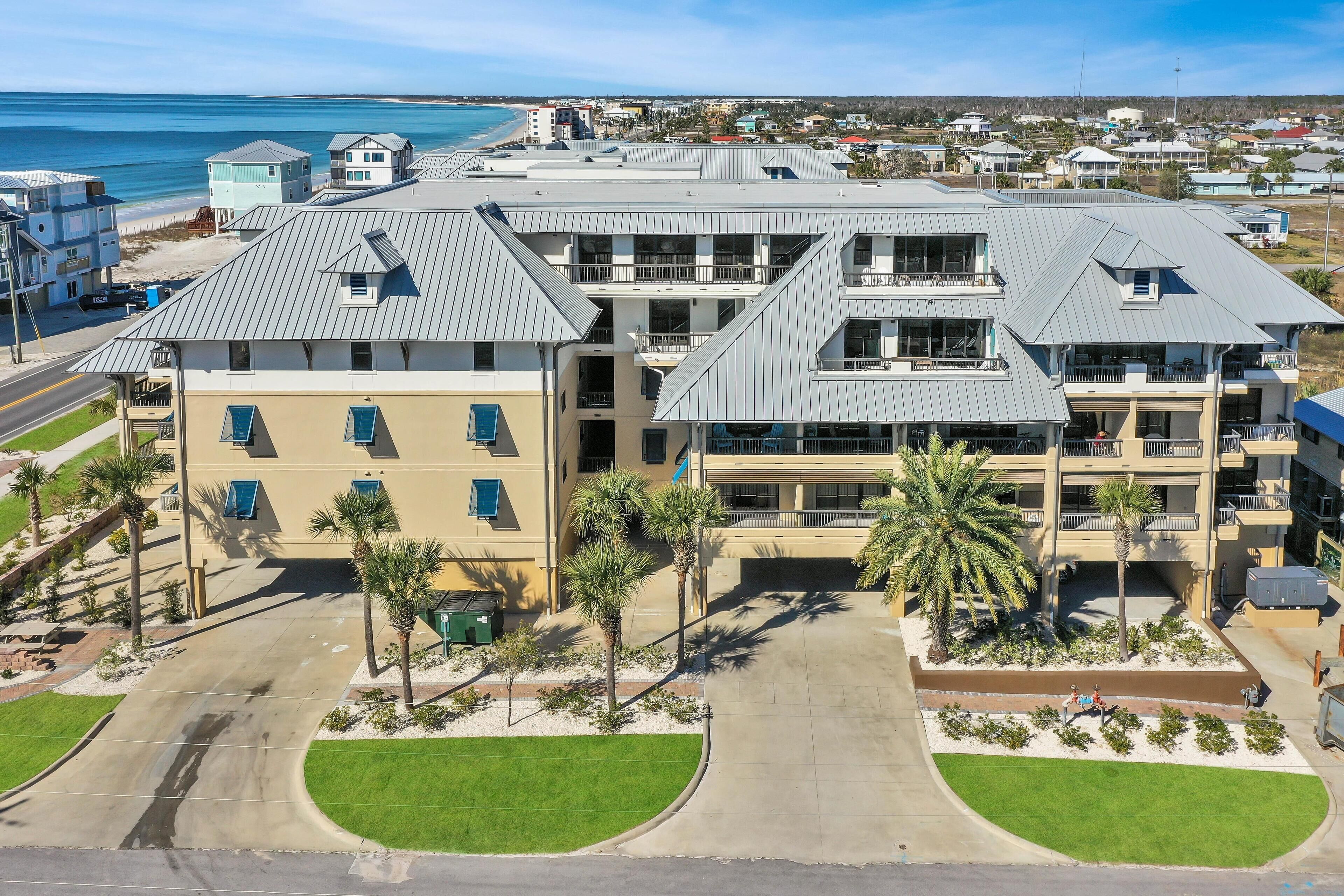 A multi-story hotel with a central courtyard, palm trees, and a view of the beach.