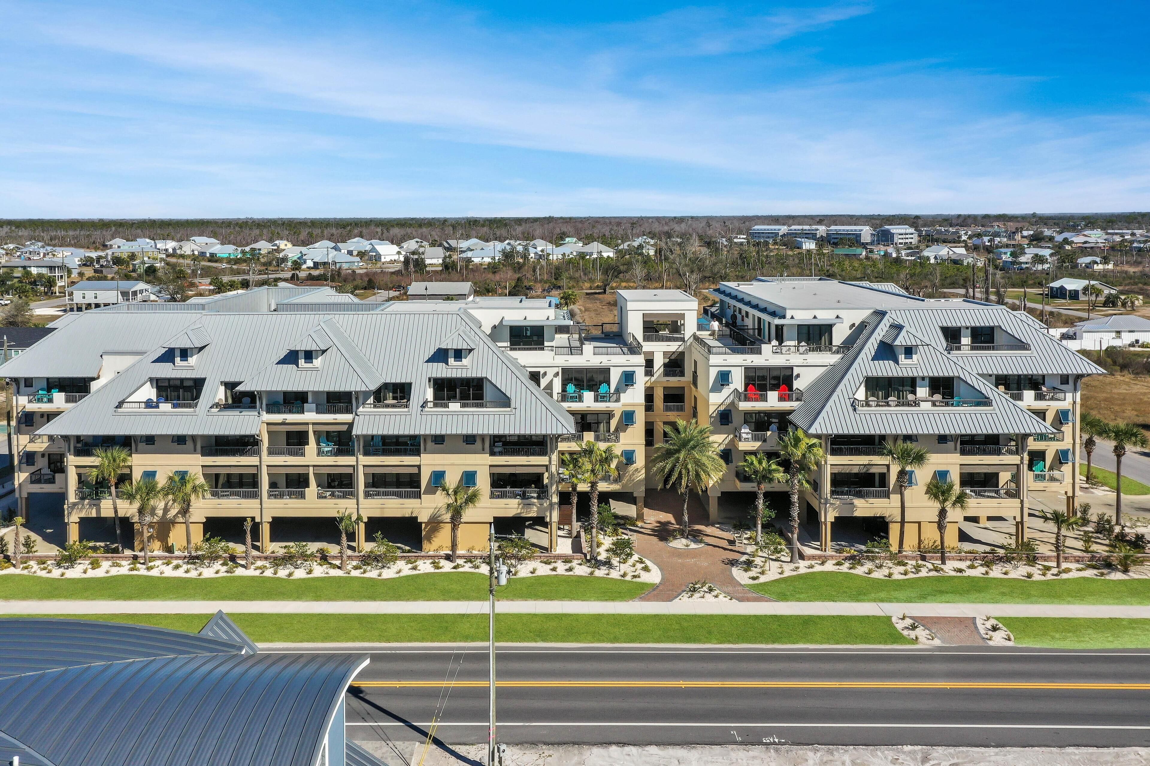 A multi-story hotel with a modern design, featuring balconies and a landscaped front yard.