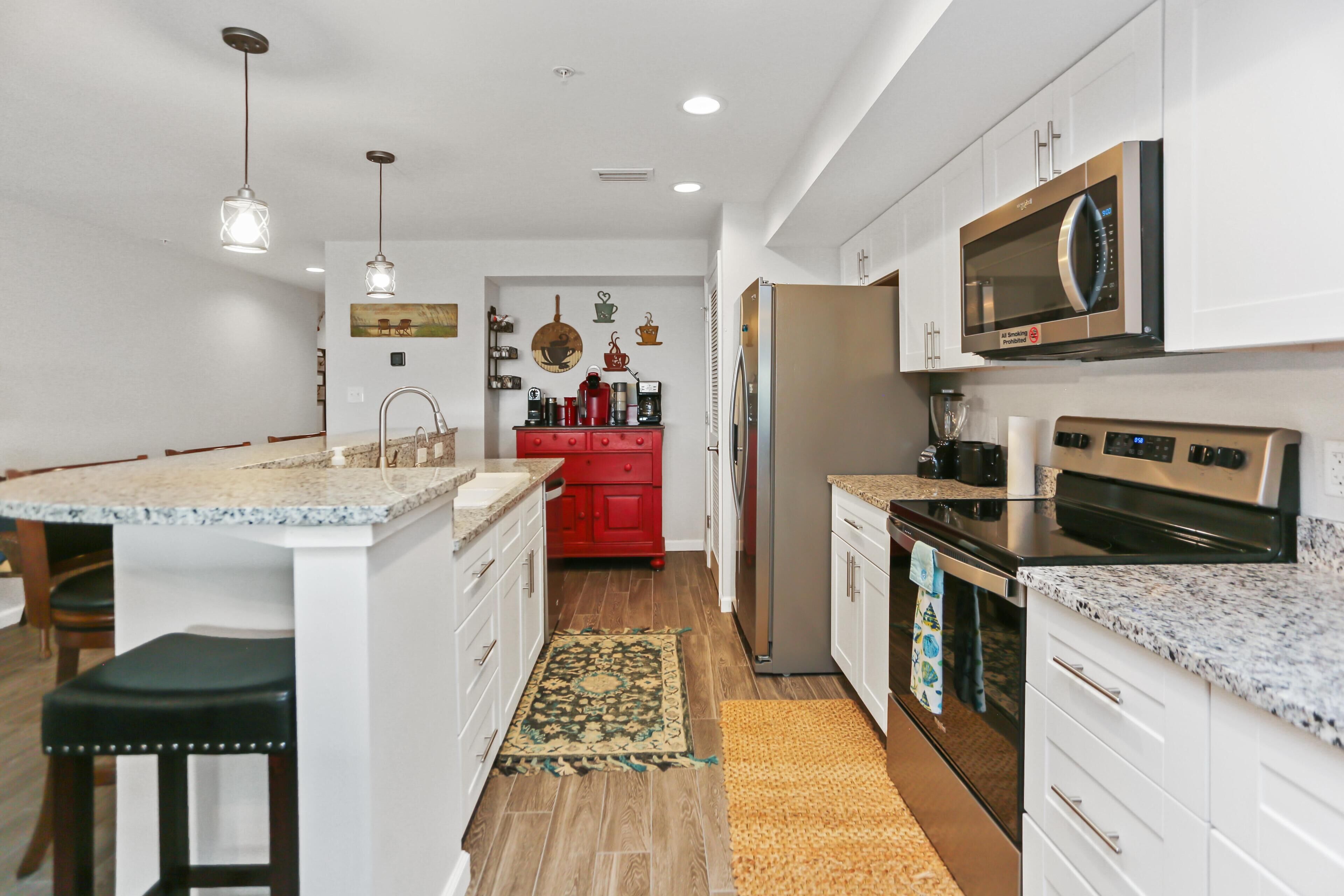 A modern kitchen with white cabinets, granite countertops, stainless steel appliances, and a central island with bar stools.
