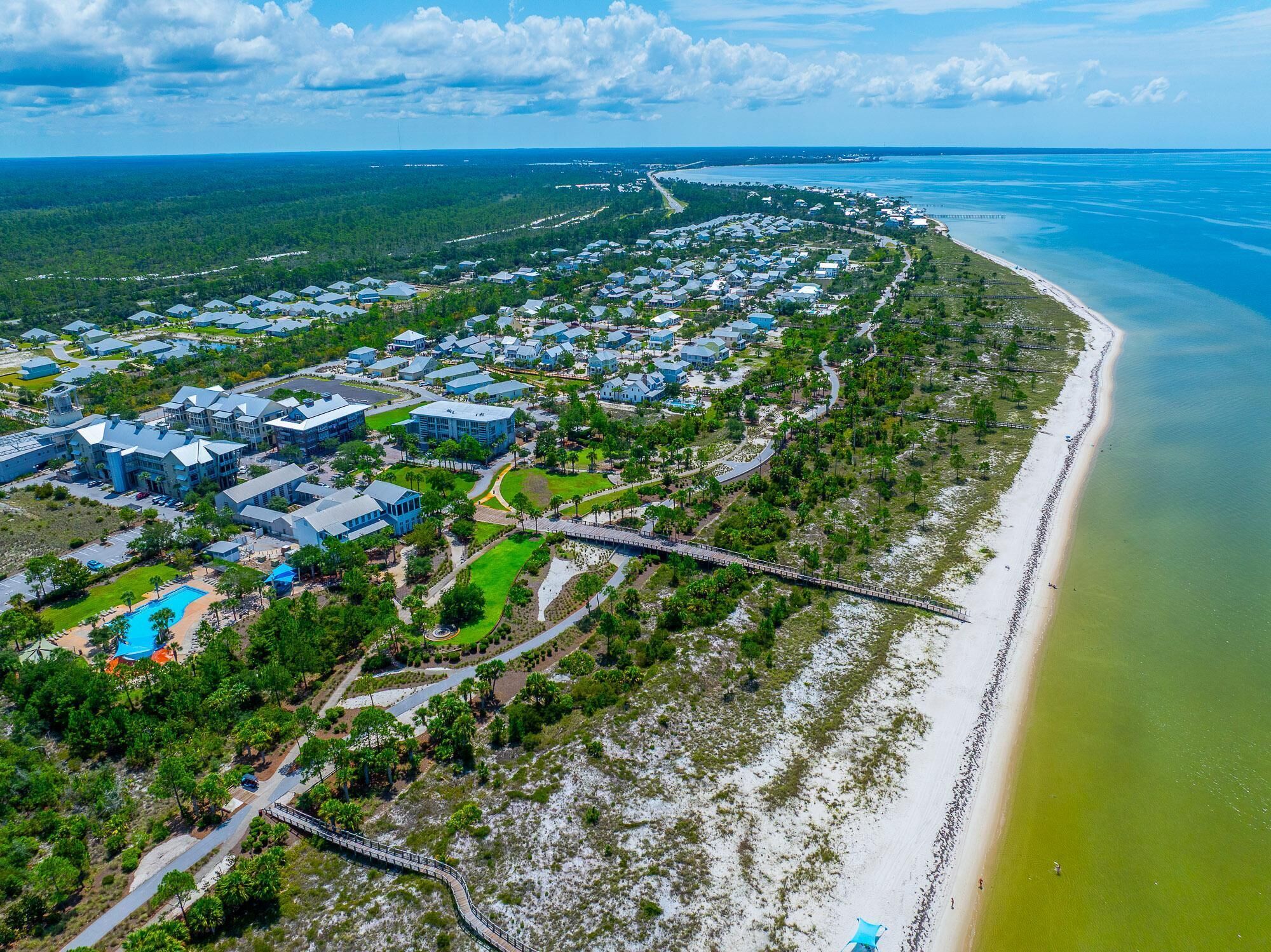 A coastal residential area with houses, a beach, and a clear sky.