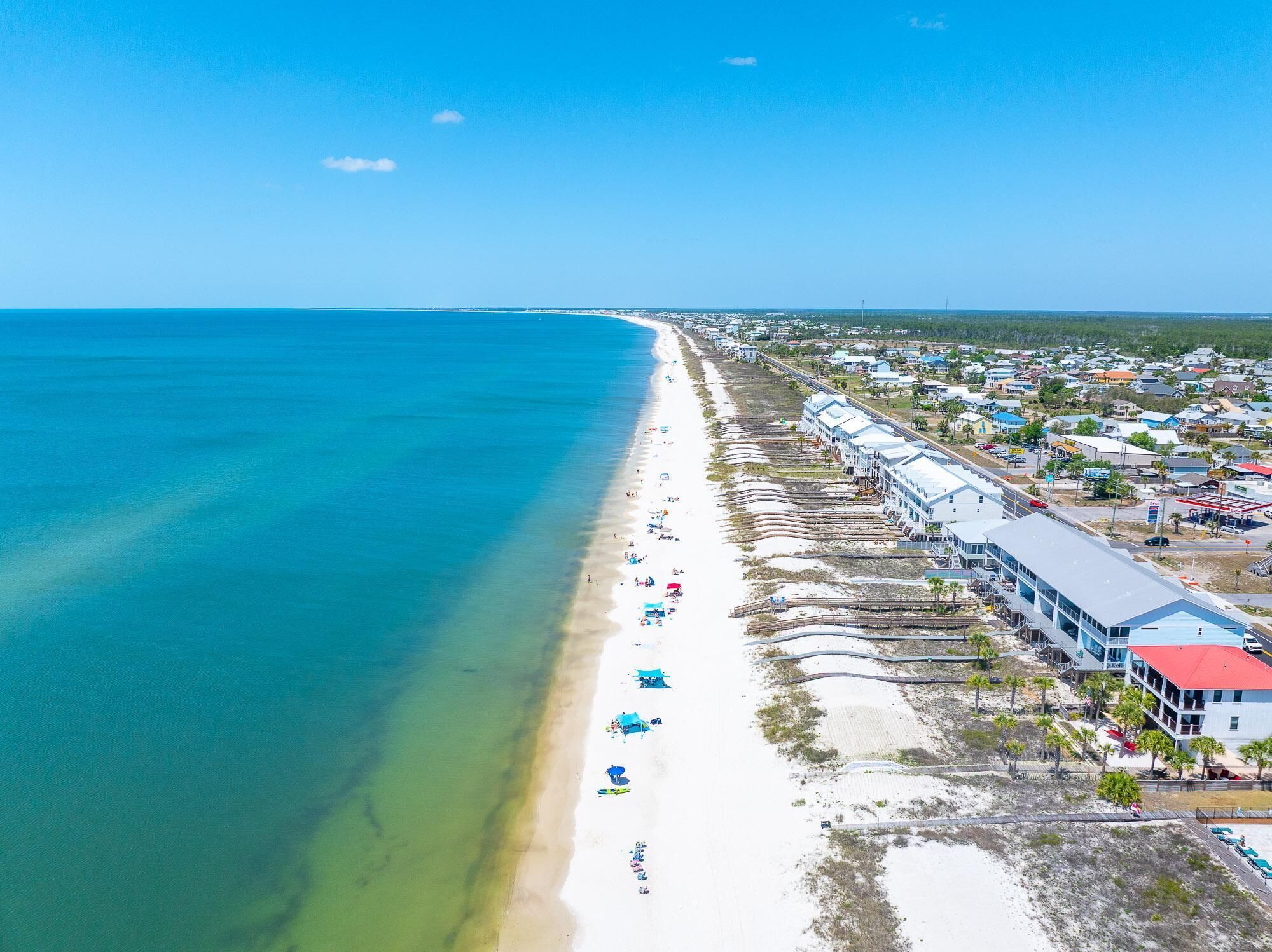 An aerial view of a beach with a row of buildings along the shore.