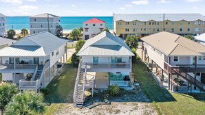 A coastal residential area with multiple two-story houses featuring balconies, a central staircase, and a view of the ocean. - The Lighthouse (Port St. Joe)