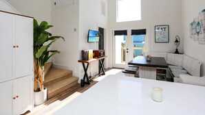 A spacious kitchen with a large island, a dining area with a white table, and a staircase leading to a balcony. - Eagle's Rest (Port St. Joe)