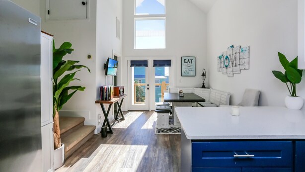 A bright kitchen with a large island, a dining area, and a staircase leading to a balcony. - Eagle's Rest (Port St. Joe)