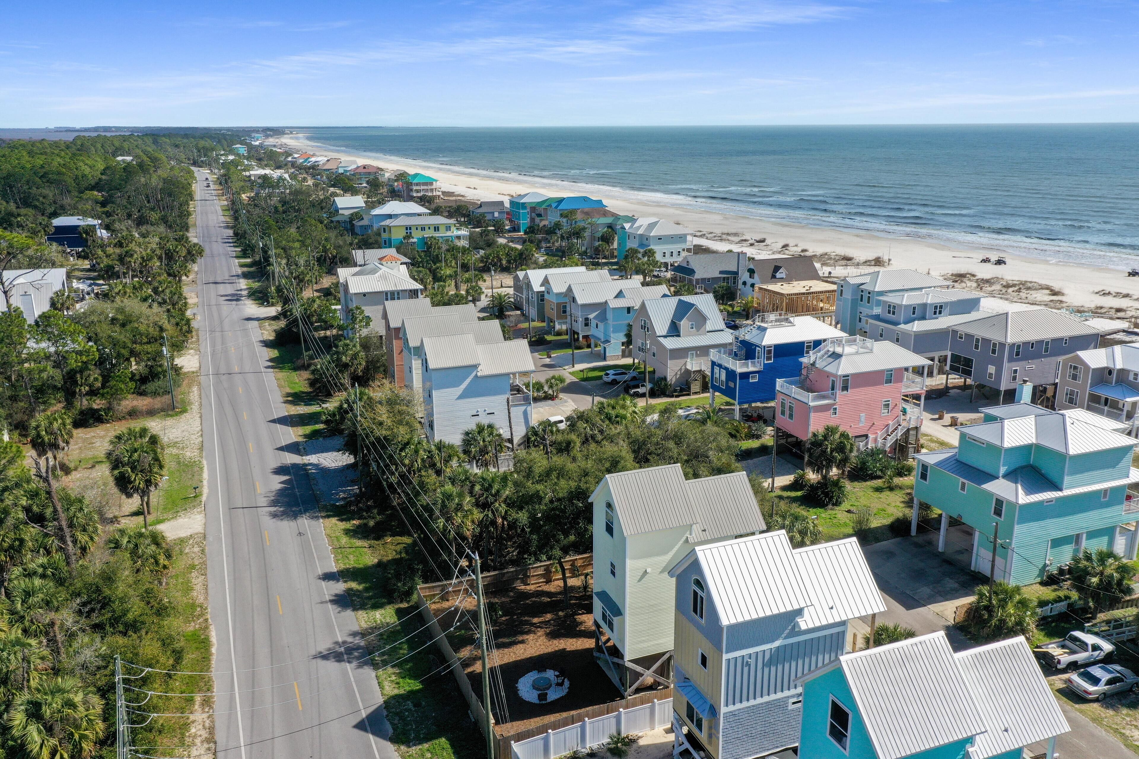 A coastal residential area with houses along a road leading to the beach.