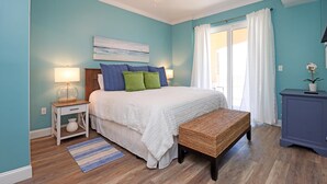 A bedroom with a bed, bedside tables, a bench, a ceiling fan, and a window with curtains. - Summerhouse 305 - Harvesting Sunshine II (Port St. Joe)