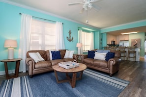 A living room with two brown leather sofas, a coffee table, and a dining area with wooden chairs. - Summerhouse 305 - Harvesting Sunshine II (Port St. Joe)