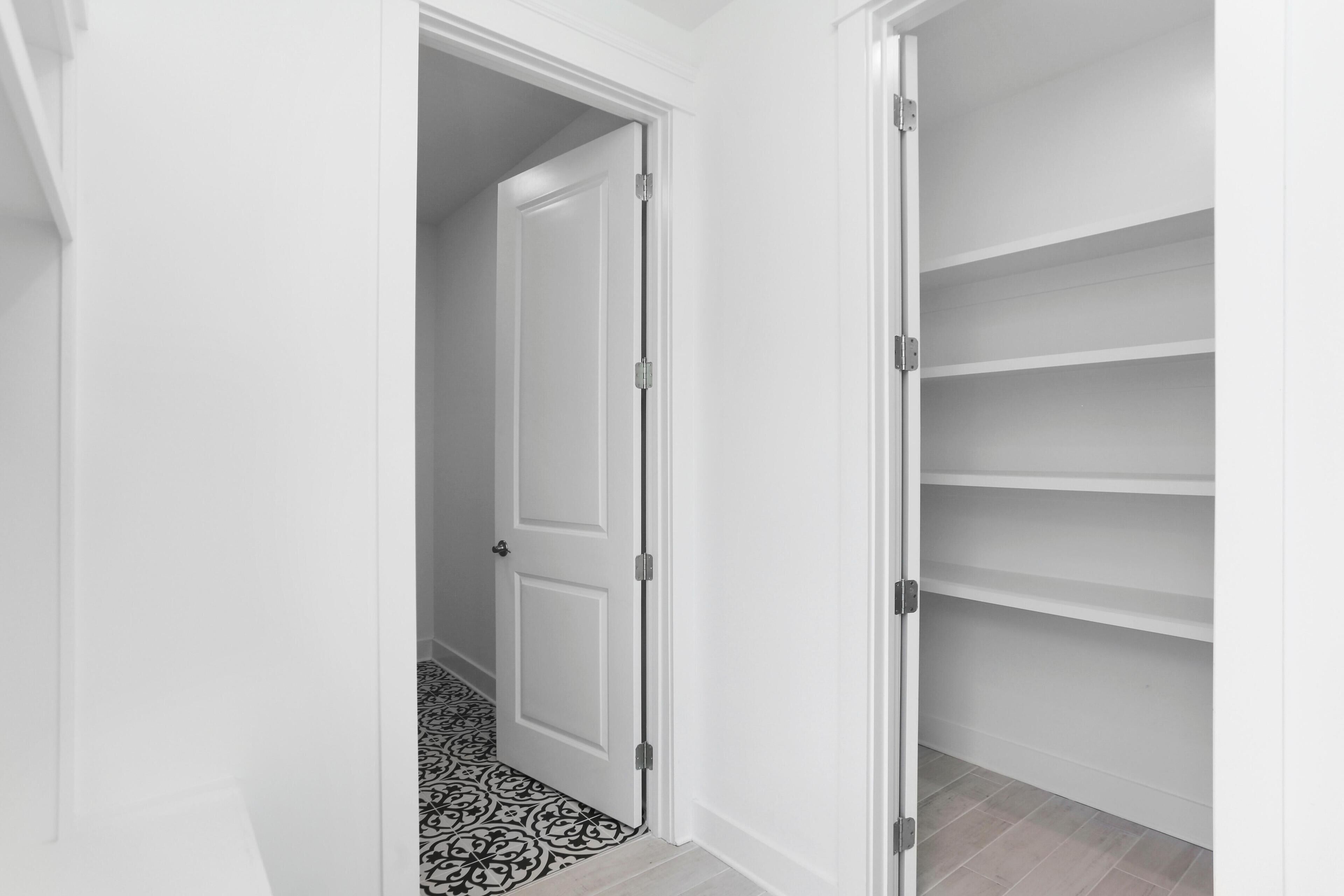 A hallway with a white door leading to a room with a patterned floor.