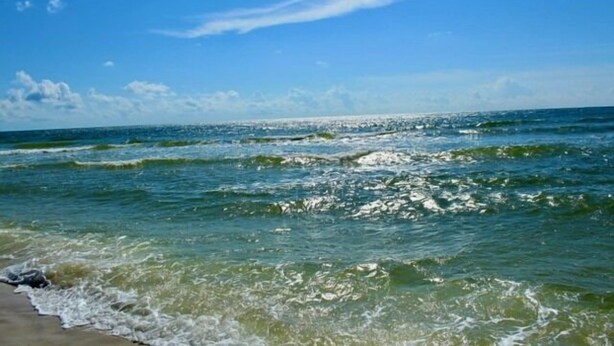 Une plage avec une eau d’un bleu limpide et des vagues.