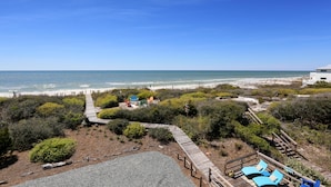 A coastal property with a wooden deck, lounge chairs, and a pathway leading to the beach. - Sea Joy (Port St. Joe)