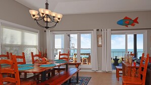 A dining area with wooden furniture, a chandelier, and a view of the ocean through large windows. - Sea Joy (Port St. Joe)