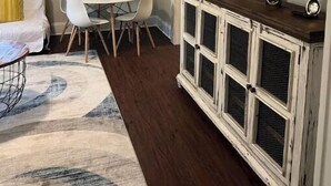 Une pièce comprenant une table à manger, des chaises, un canapé, un téléviseur fixé au mur et un meuble contenant des objets décoratifs.