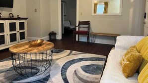Un salon avec un canapé, une table basse, un téléviseur et une horloge au mur.