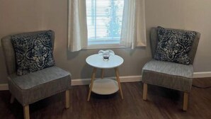 A room with two armchairs, a small round table, and a window with curtains.