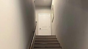 A staircase with wooden handrails leading to a white door at the top.