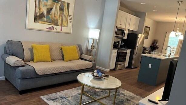 A living room with a grey sofa, yellow cushions, a round coffee table, and a painting on the wall.