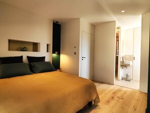 Ein Schlafzimmer mit einem Bett, einem Kleiderschrank, einer Tür zu einem Badezimmer und einem kleinen Regal mit einer Pflanze.