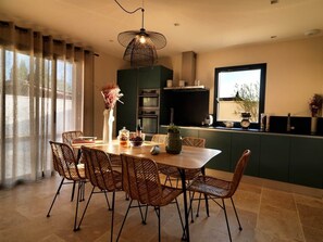 Eine moderne Küche mit Essbereich, ausgestattet mit einem Tisch und Stühlen, einer Pendelleuchte und Blick ins Freie.