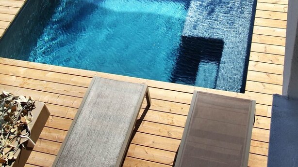 Ein rechteckiger Pool mit umlaufender Holzterrasse.
