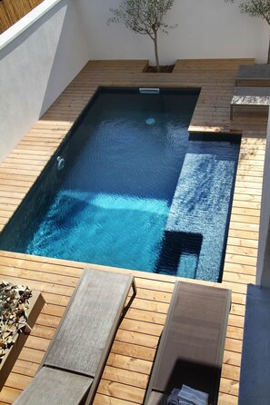 Une piscine rectangulaire entourée d’une terrasse en bois.