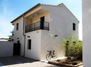 Un bâtiment moderne à deux étages, doté d’un balcon, d’un vélo et d’un petit jardin.