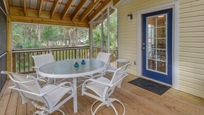 A covered outdoor area with a round table and chairs, a ceiling fan, and a view of the outdoors.