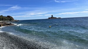A rocky shoreline with clear blue water and a distant island. - Comfortable nest with pool and sea view (Saint-Raphaël)