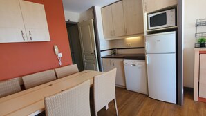 A compact kitchen with a dining area, featuring a microwave, dishwasher, and a built-in oven. - Comfortable nest with pool and sea view (Saint-Raphaël)