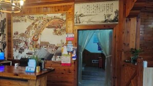 A wooden interior with a reception desk, a mural, and a traditional Chinese painting. - Lake House (Taishun)