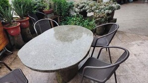 An outdoor patio with a round stone table surrounded by wicker chairs. - Lake House (Taishun)