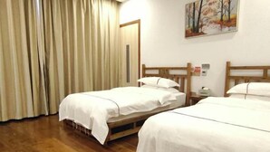 A room with two wooden beds, a wooden floor, a painting on the wall, and a door with a vertical handle. - Lake House (Taishun)