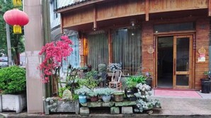 A wooden building with a porch area decorated with various potted plants and flowers. - Lake House (Taishun)