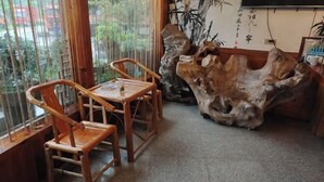 A room with a wooden table and chairs, a large wooden sculpture, and a view through a window. - Lake House (Taishun)