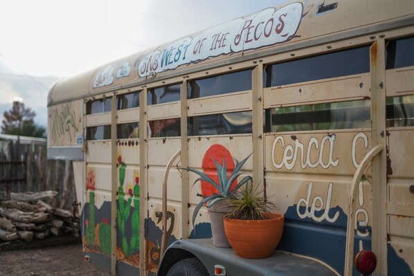 Un autobus d’époque, orné de peintures murales colorées, avec une plante en pot à l’arrière.