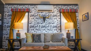 A living room with a sofa, two lamps, a decorative bull skull, patterned wallpaper, and curtains. - Panoramic Porch View Close to Town @ Casa Pequena (Alpine)