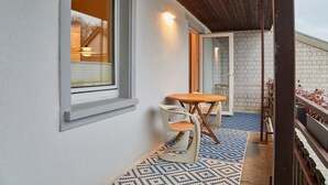 A balcony with a patterned floor, a wooden table, and two chairs. - Air-conditioned apartment with balcony - Deidesheim (Deidesheim)