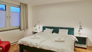 A neatly arranged bedroom with a bed, bedside tables, and a window with curtains. - Air-conditioned apartment with balcony - Deidesheim (Deidesheim)