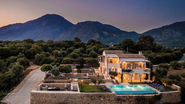 A two-story villa with a swimming pool, surrounded by lush greenery and mountains in the background. - Villa Comi (Kefalonia)