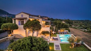 A villa with a swimming pool, surrounded by lush greenery and a mountainous backdrop. - Villa Comi (Kefalonia)