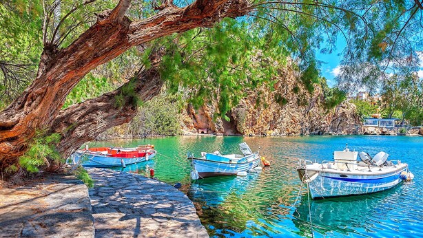 A serene waterfront with boats docked, a stone pathway, and lush greenery. - Villa Carolina Private Pool (Agios Nikolaos)