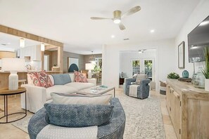 Een moderne woonkamer met een bank, salontafel en een plafondventilator.