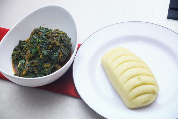 Un tazón blanco con vegetales verdes y un plato blanco con un alimento enrollado.