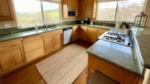 Una cocina con gabinetes de madera, estufa a gas, microondas y lavavajillas.