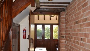 A wooden staircase leading to a room with a brick wall, a wooden table, and a fire extinguisher. - Hayloft Barn - Lodge Barns , Country Get Away, Morton near Southwell (Nottinghamshire)