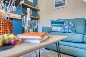 A living room with a blue sofa, a wooden coffee table, and a bookshelf.