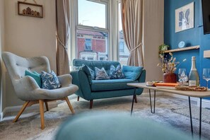 A living room with a sofa, armchair, and a table with decorative items.