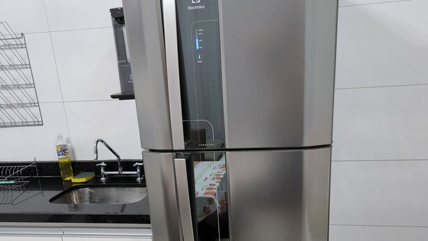 Ein Küchenschrank mit Edelstahlkühlschrank, Wasserspender, Spüle und Geschirrgestell.