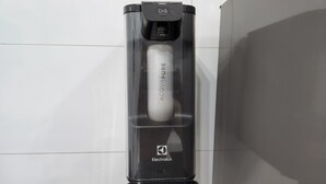 Eine schwarze elektrische Zahnbürste mit einer transparenten Ladestation, beschriftet mit 'Electrolux'.