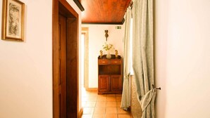 Ein Flur mit einer Holztür, einem gerahmten Bild an der Wand, einem Schrank mit Dekorationen und einem Vorhang.